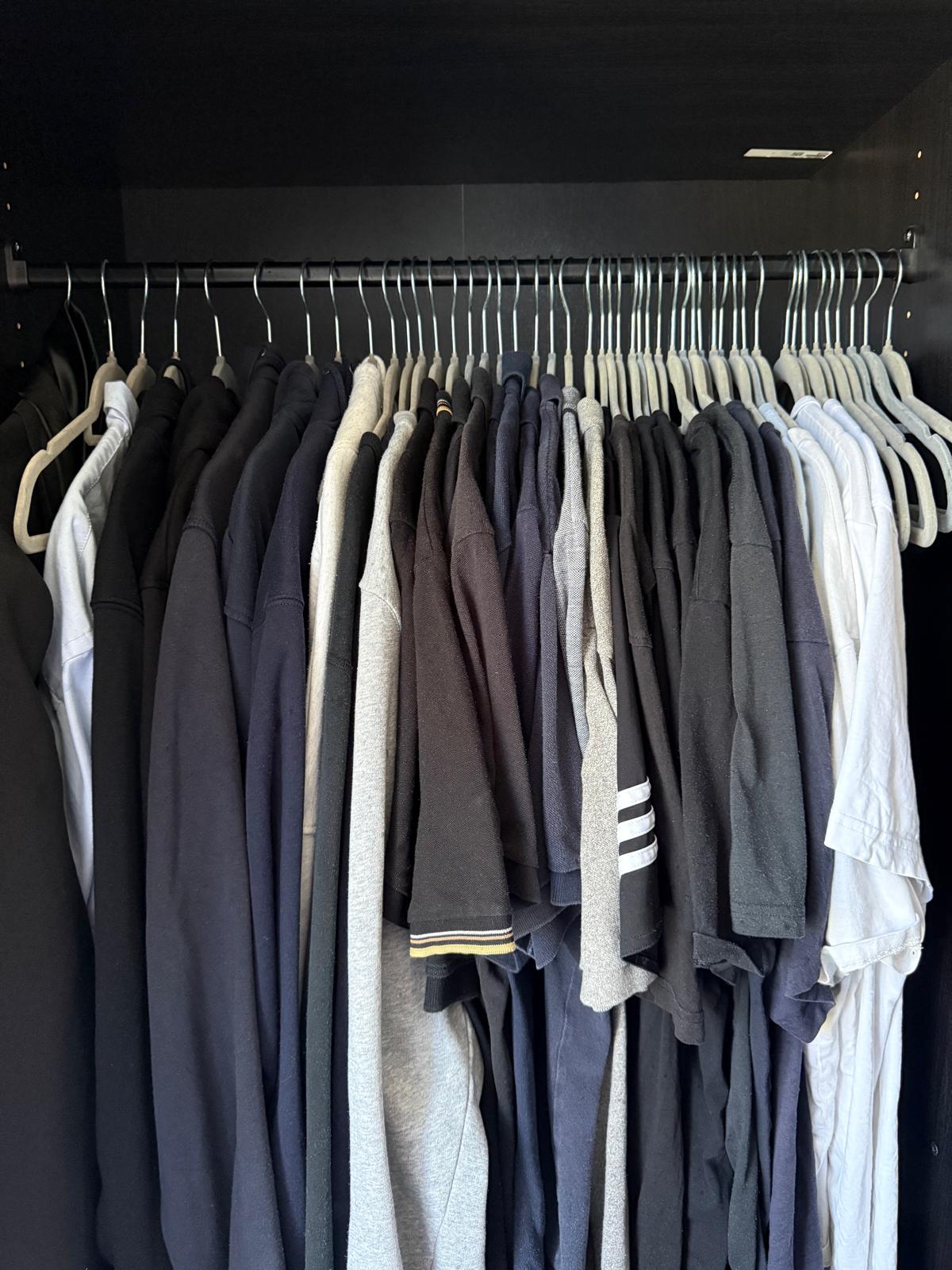 Wardrobe rail close-up with tops and shirts hung neatly on matching slim velvet hangers
