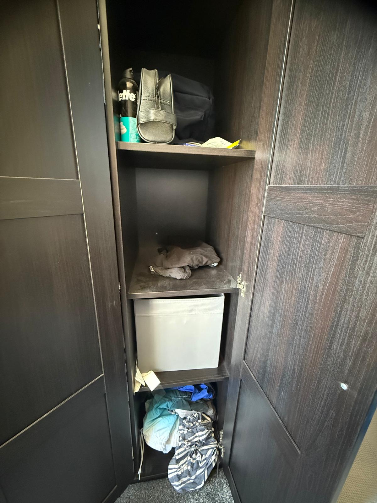 Untidy wardrobe interior with loose items and a fabric storage box before organisation