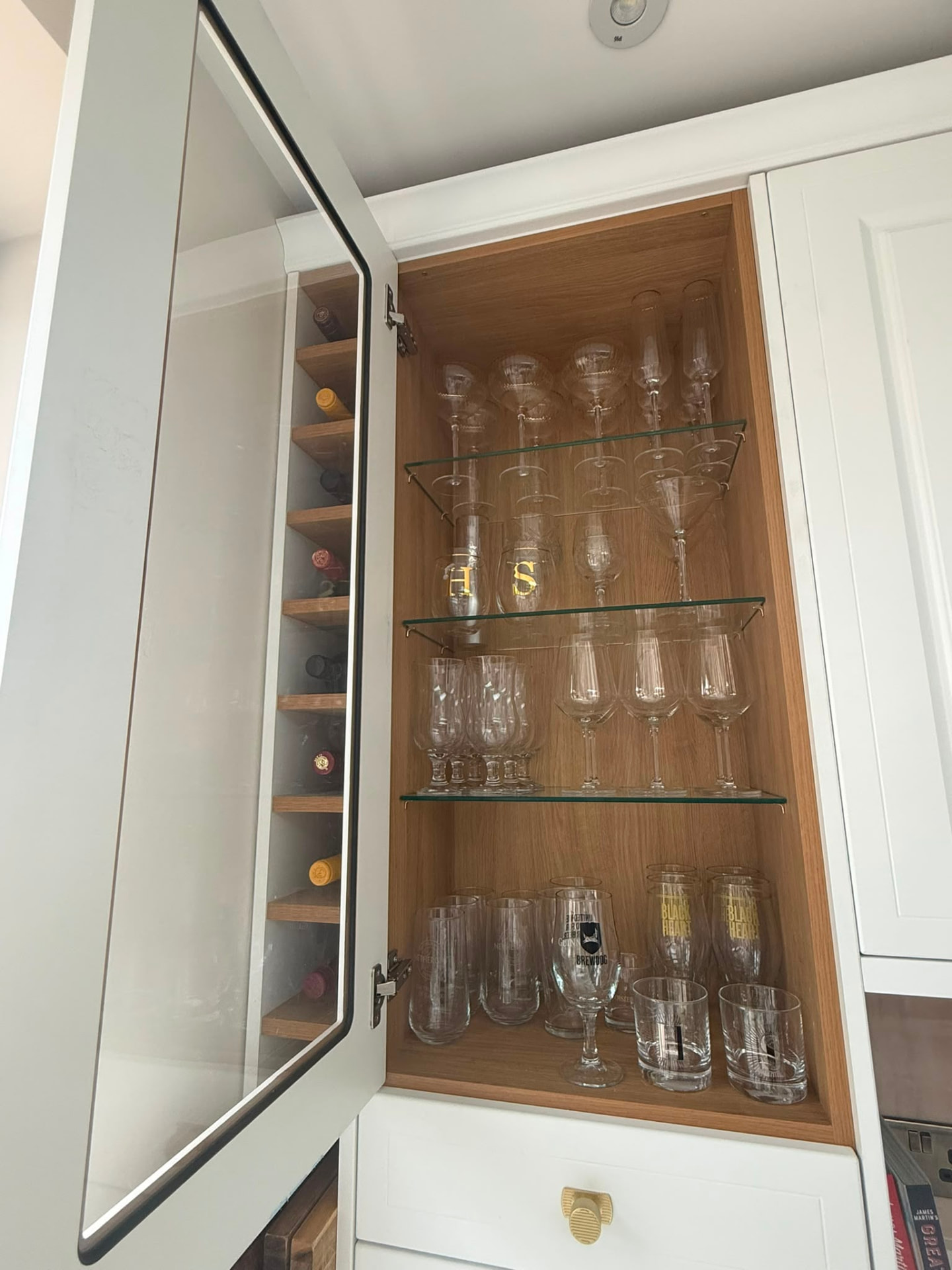 Kitchen drinks cabinet with glassware and stemware organised on tempered glass shelves