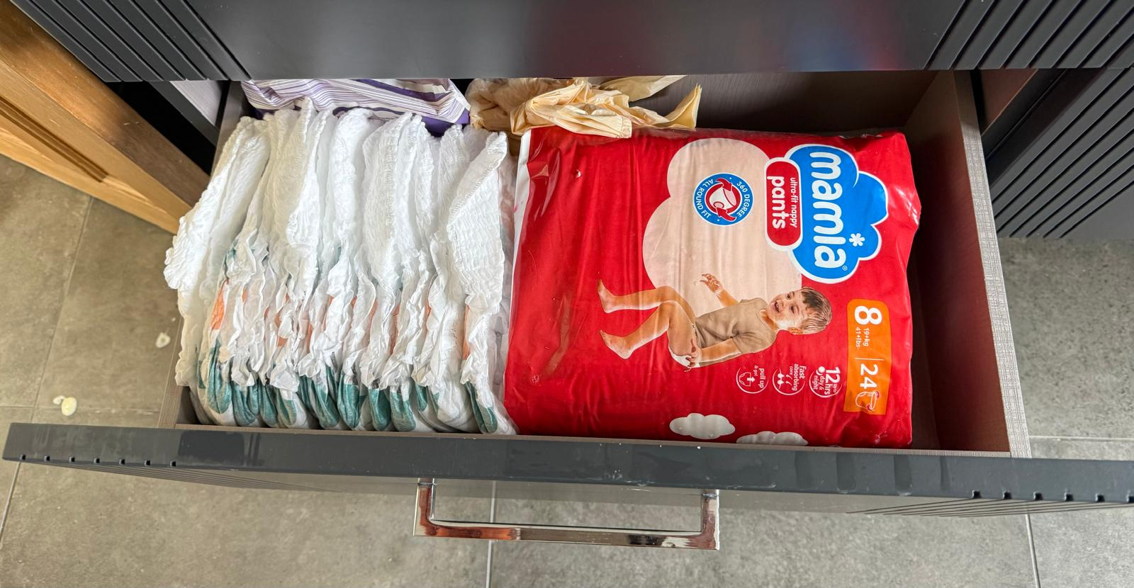 Same kitchen drawer after organising, with nappies stacked and packs aligned