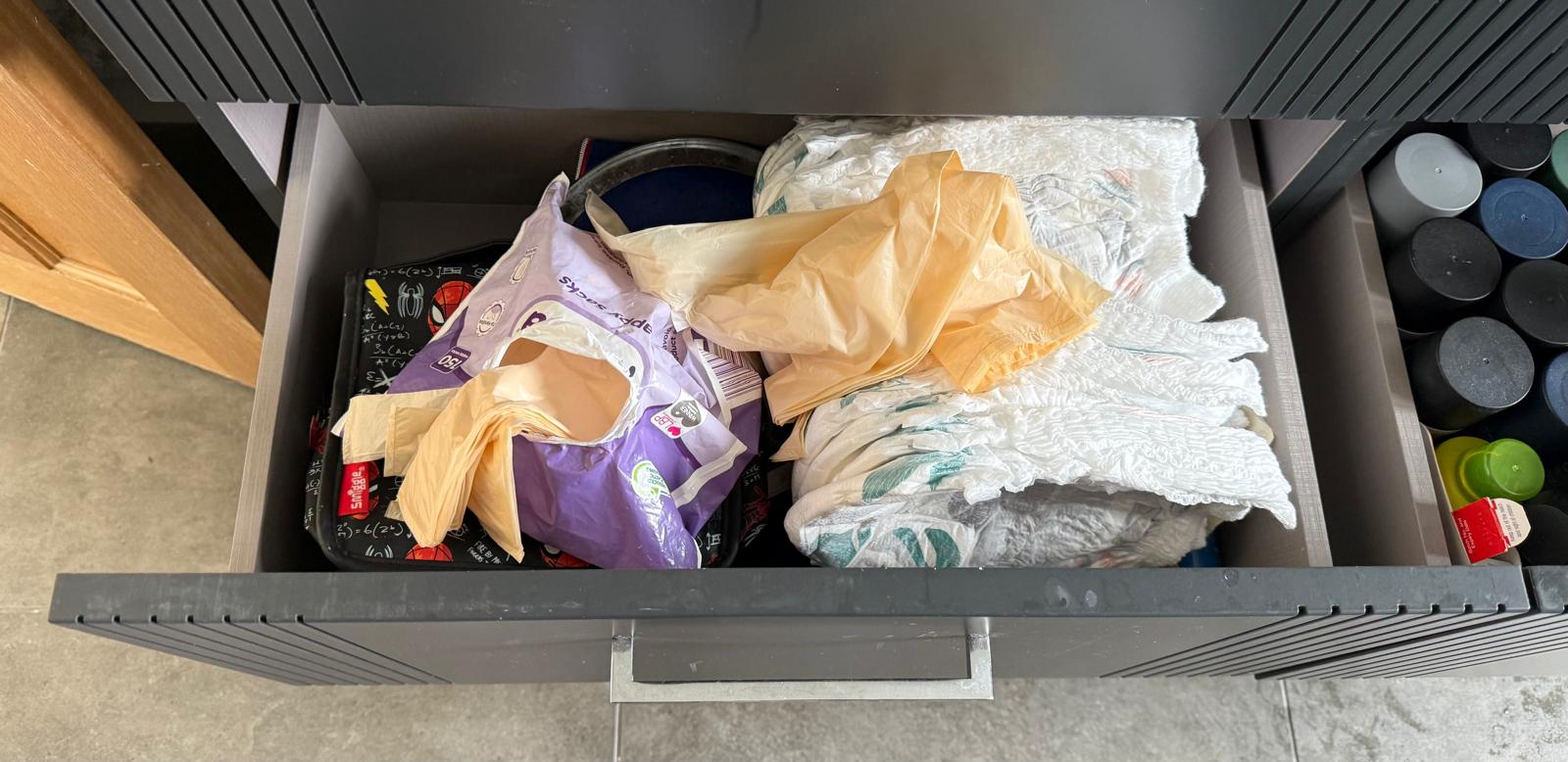 Overflowing family drawer of nappies and baby supplies before an organisation session